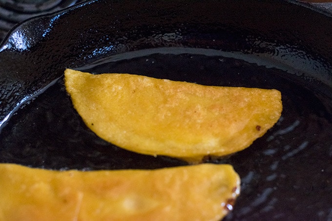two cheese quesadillas frying in a cast iron skillet