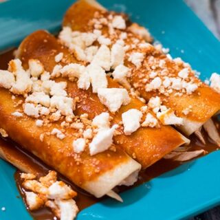 red authentic chicken enchiladas recipe on a blue plate