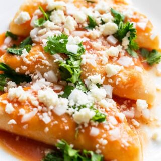 entomatadas garnished with onion, cilantro and queso fresco