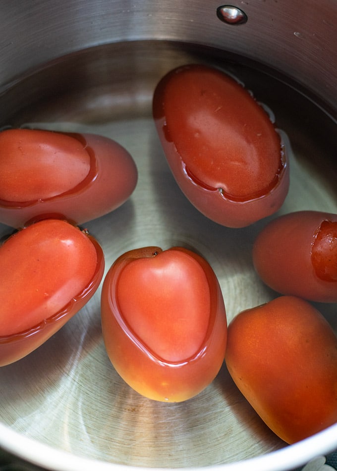 six roma tomatoes in a pot covered with water
