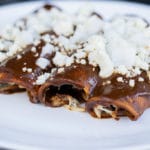 chicken mole enchiladas garnished with queso fresco and diced onion