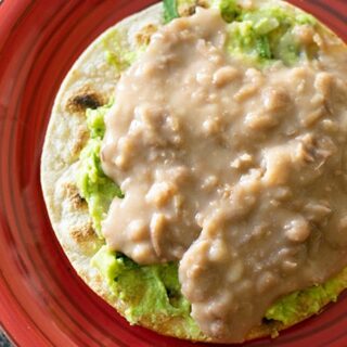 refried bean tostada with guacamole on a plate