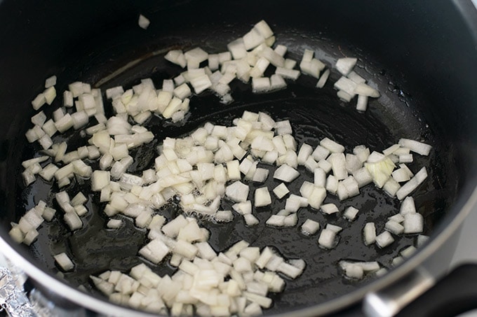 diced onion cooking in bacon grease in a pot