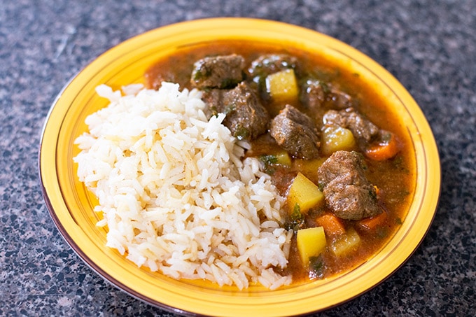 Mexican beef stew with white rice on a yellow plate.