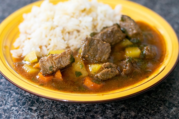 Guisado de res with white rice on a yellow plate.