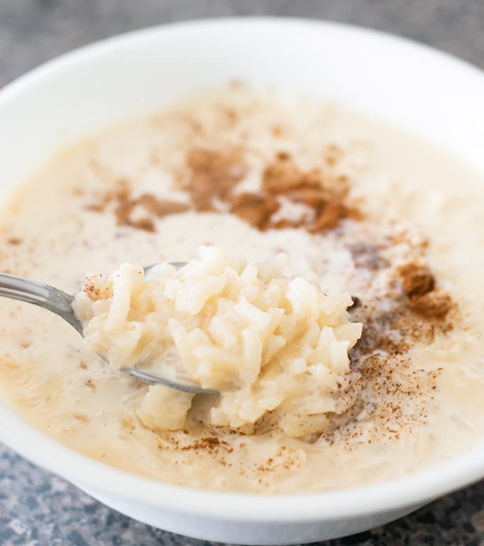 Mexican rice pudding in a white bowl with ground cinnamon.