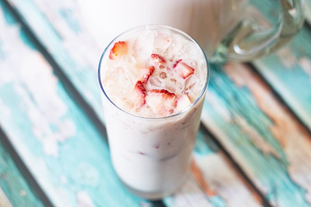 strawberry horchata in a glass with chopped strawberries