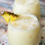 pina colada agua fresca in two glasses garnished with a slice of pineapple
