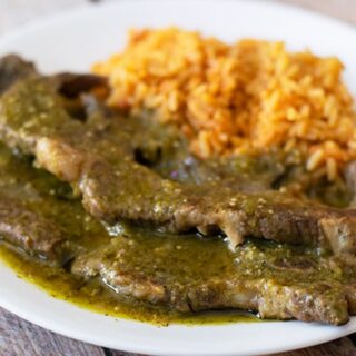 costillas de res en salsa verde with rice on a white plate