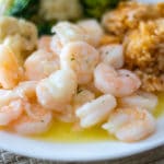 garlic butter shrimp with rice and steamed veggies on a white plate