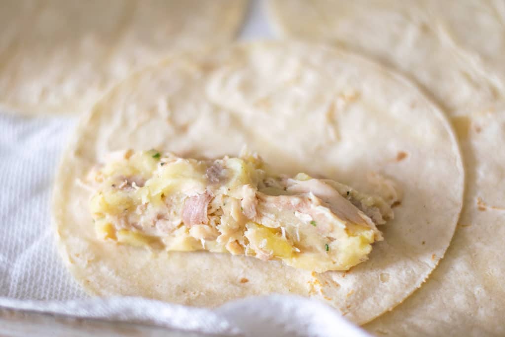 filling tortillas with a shredded chicken and potato mixture