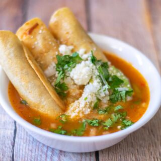 chicken taquitos served in a white bowl with consome