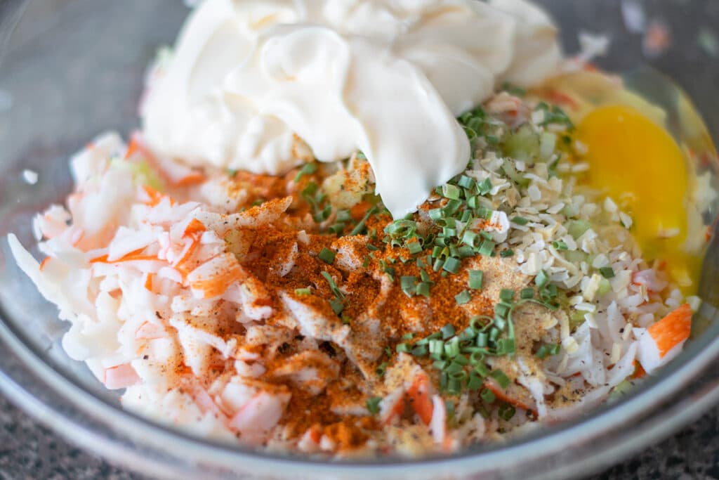 a mixing bowl with imitation crab meat and seasonings.