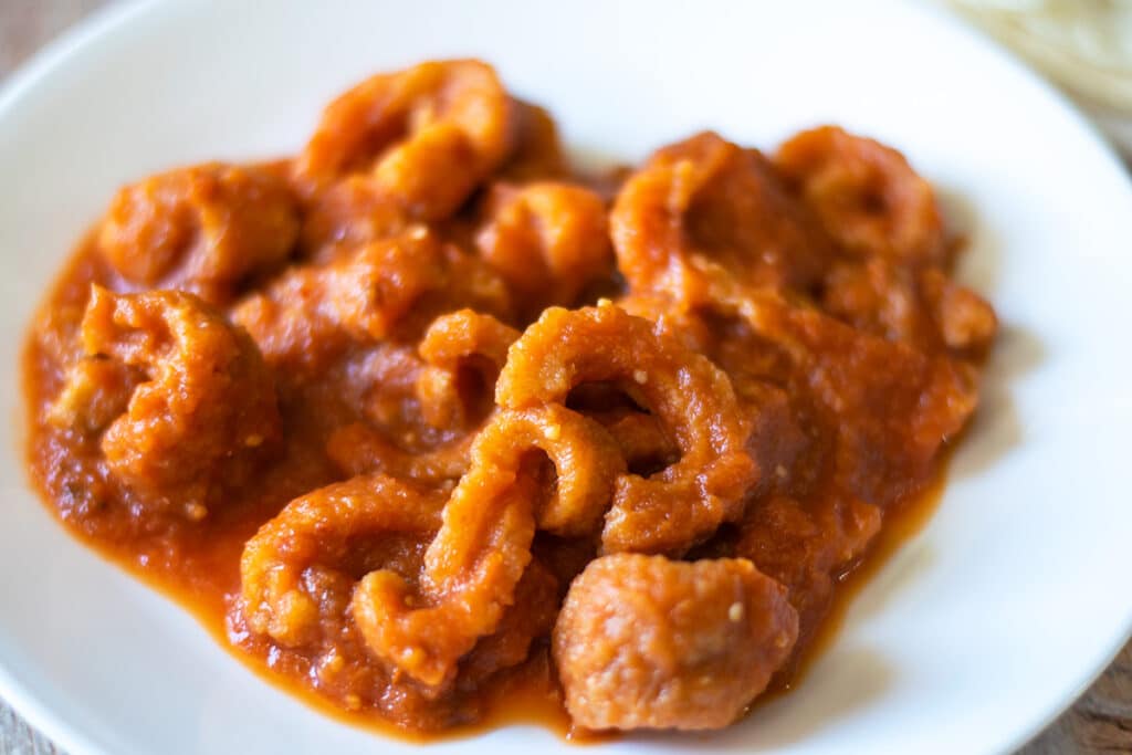 Pork cracklings in red salsa on a white plate