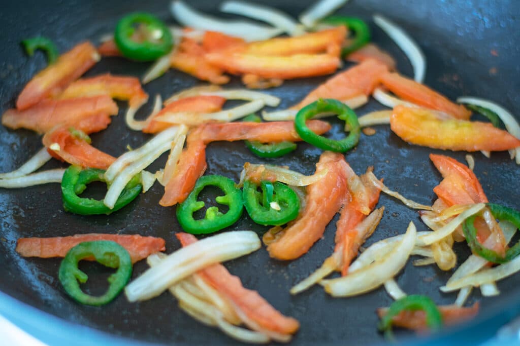 Cooking onion, jalapeno and tomato in olive oil in a skillet.