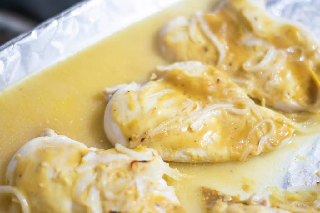baked chicken breasts in mustard sauce on a baking sheet