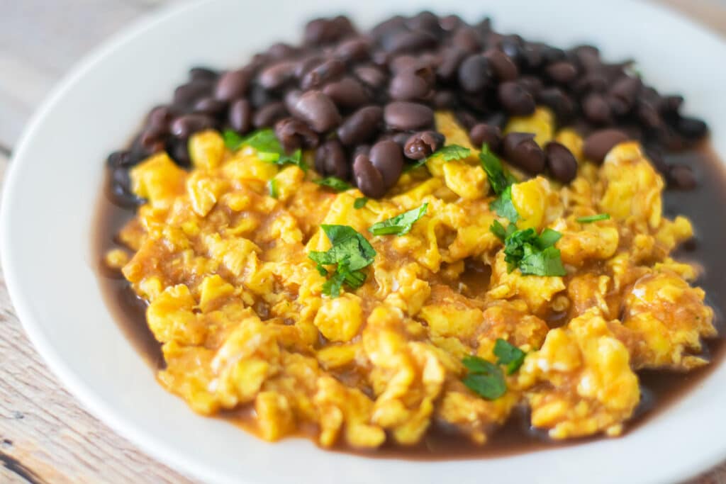 eggs in salsa and black beans on a white plate