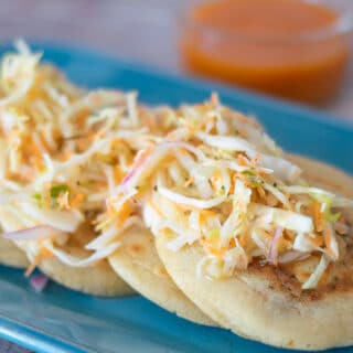 pork and cheese pupusas with curtido on a blue plate.