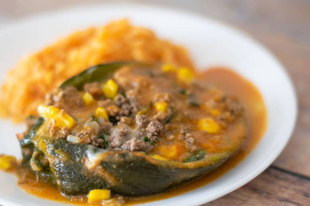 a ground beef stuffed poblano pepper and rice on a white plate.