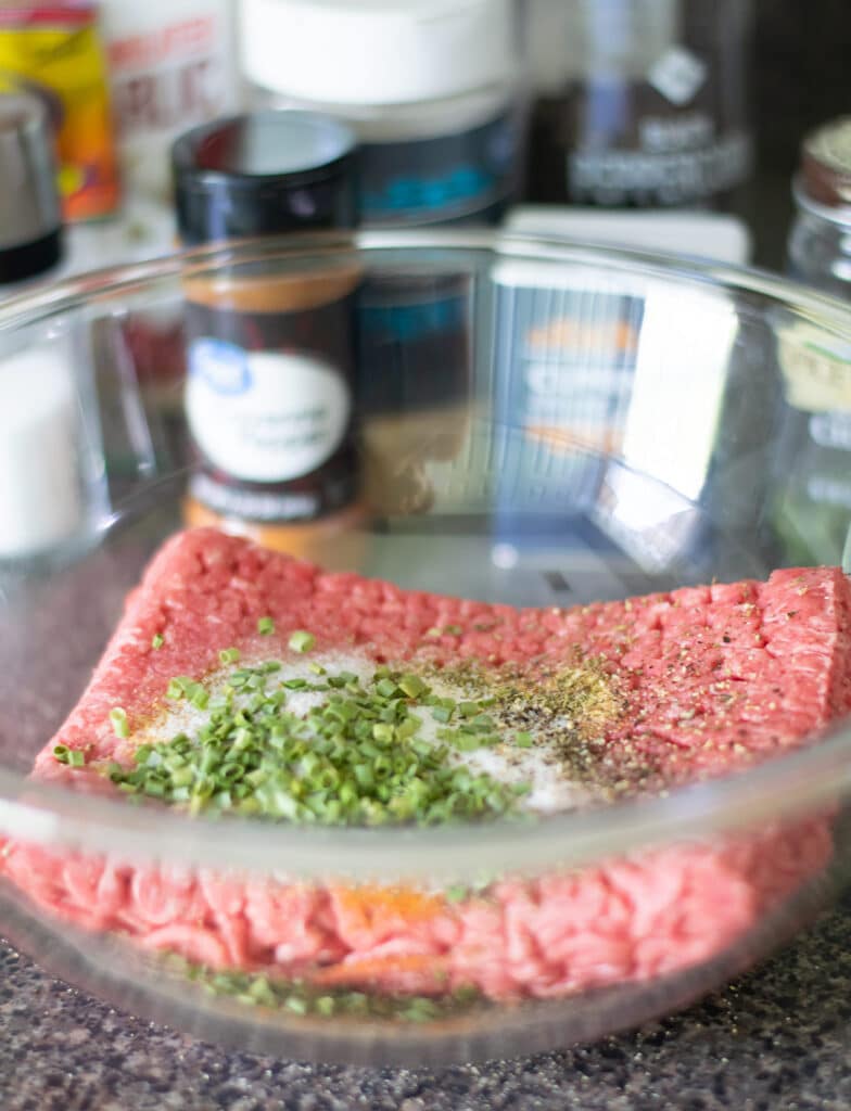 ground beef and seasonings in a glass bowl.