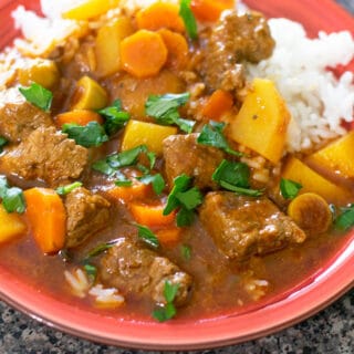 carne guisada and white rice on a red plate.