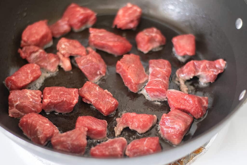 Browning stew meat in a skillet.