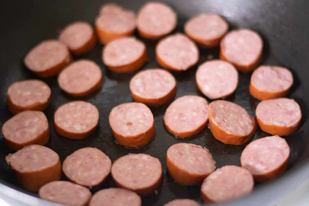 cooking smoked sausage in a skillet.