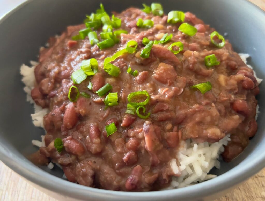 A bowl of red beans and rice with sliced green onions.