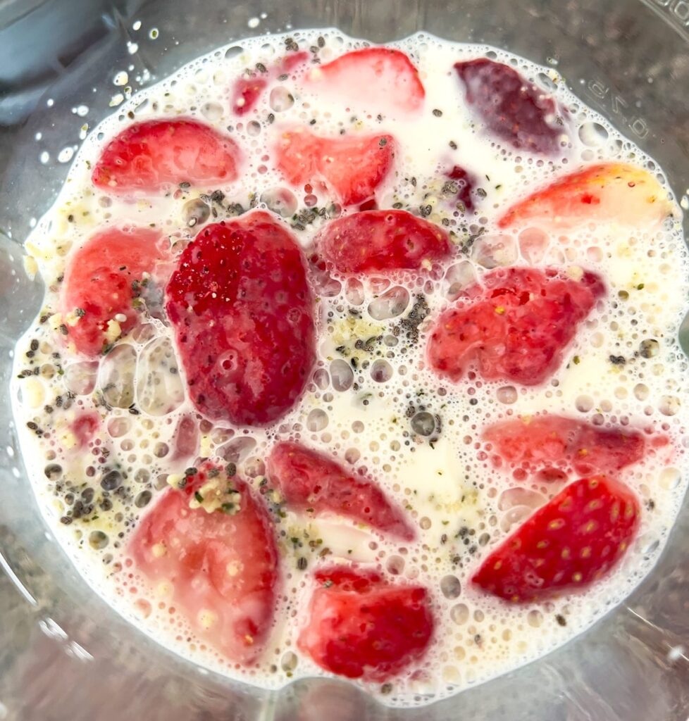 Ingredients for strawberry oat milk smoothie in blender.