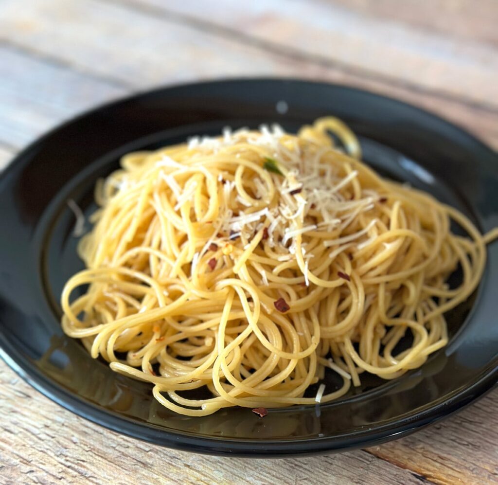Asian garlic noodles on a black plate.