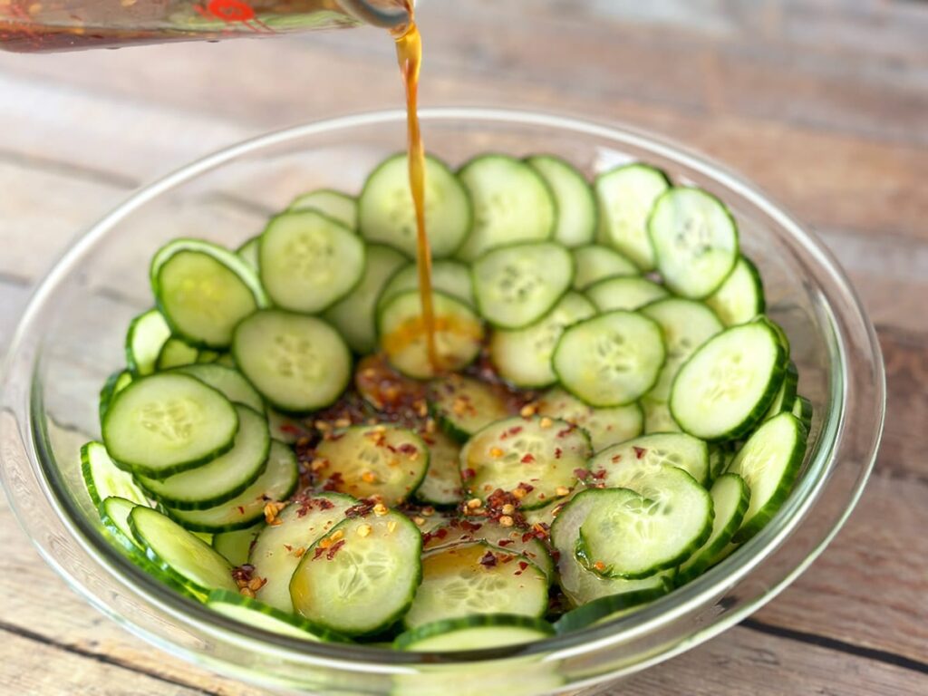 Pouring dressing over cucumbers.