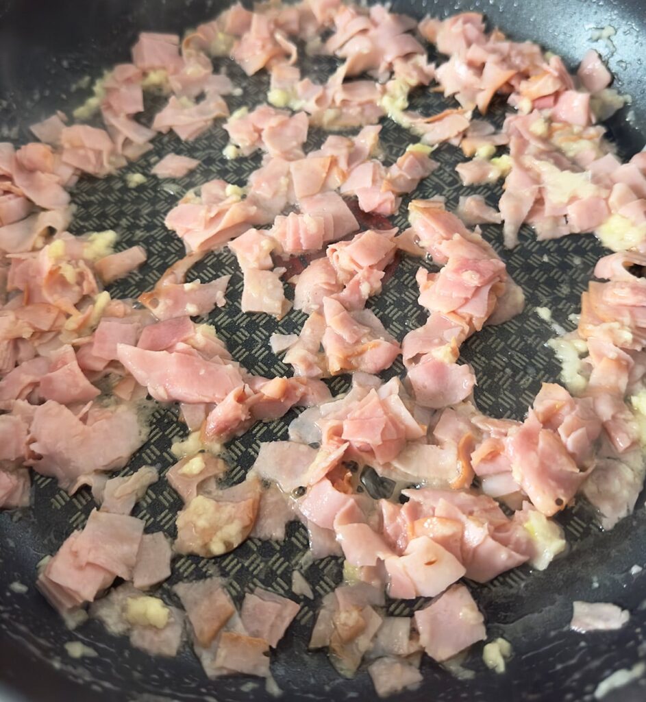 Sautéing ham, onion and garlic in butter.