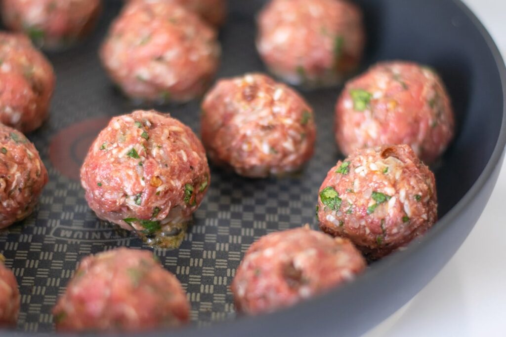 Browning Mexican meatballs in a skillet.