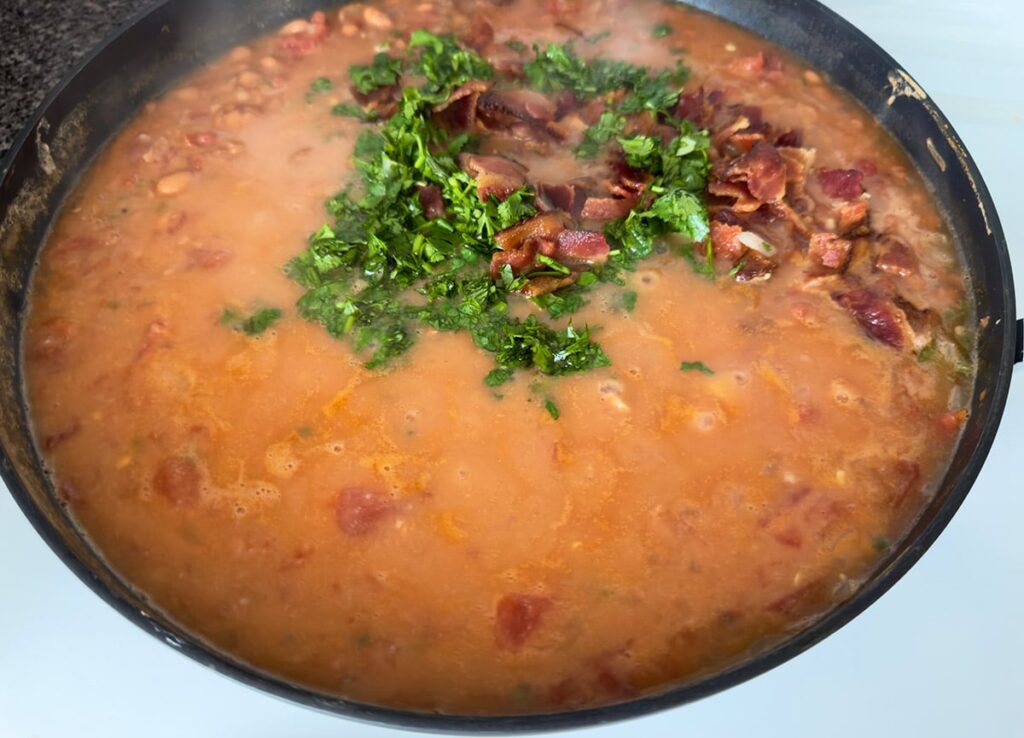 Beans with bacon and cilantro in a skillet.
