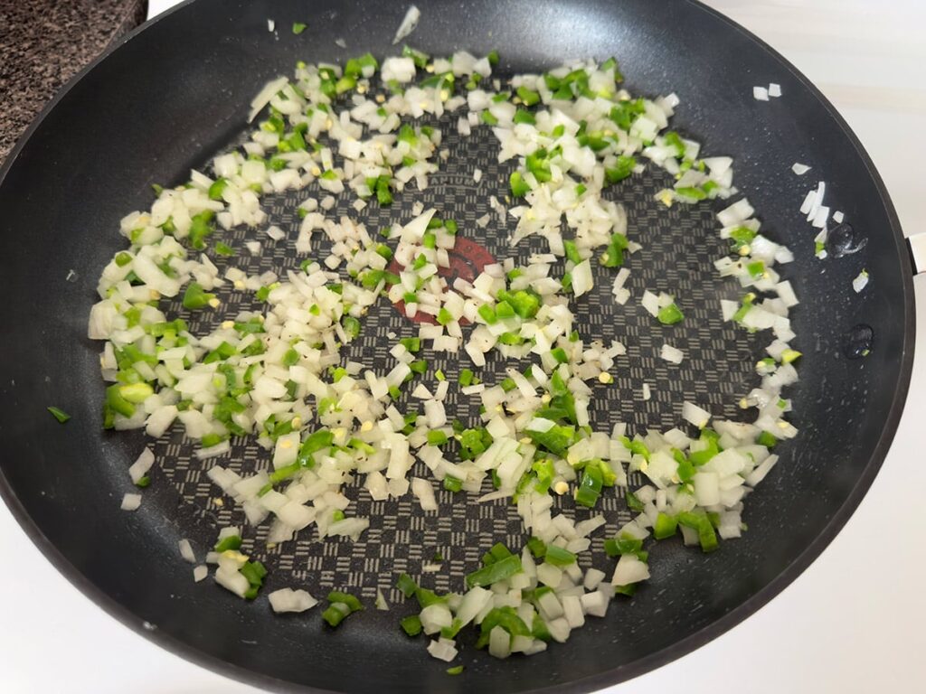 Sauteeing onion and jalapeno in a skillet.