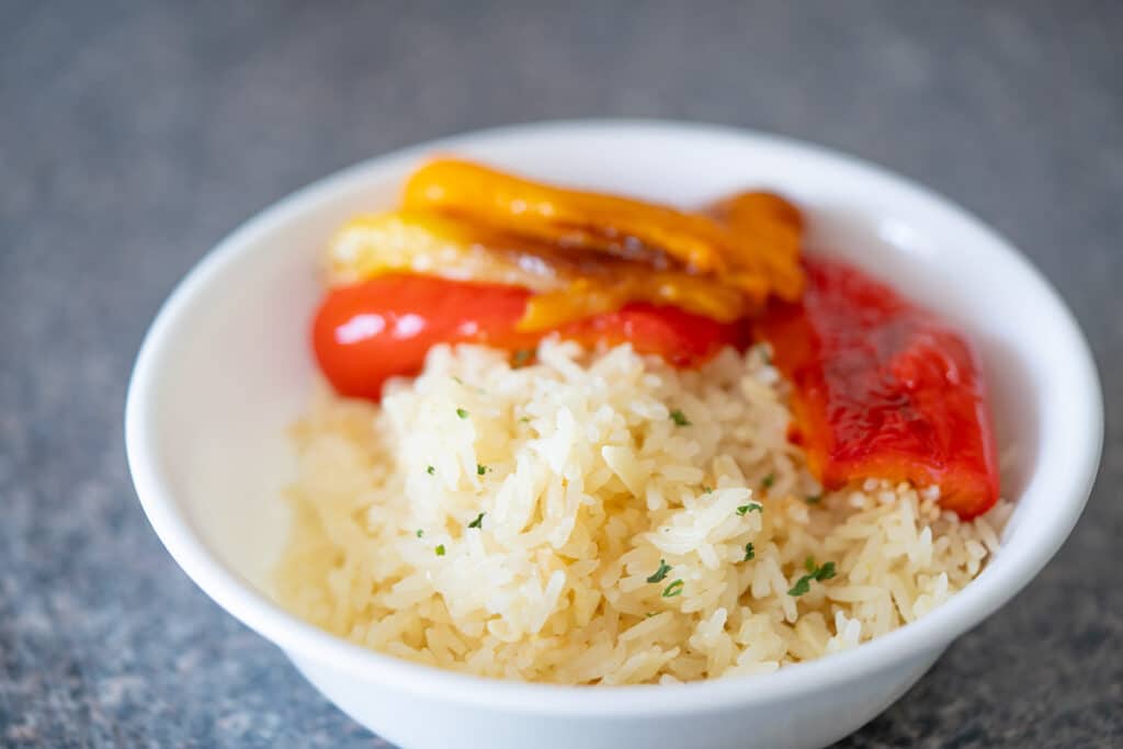 Rice pilaf and roasted bell peppers in a white bowl.