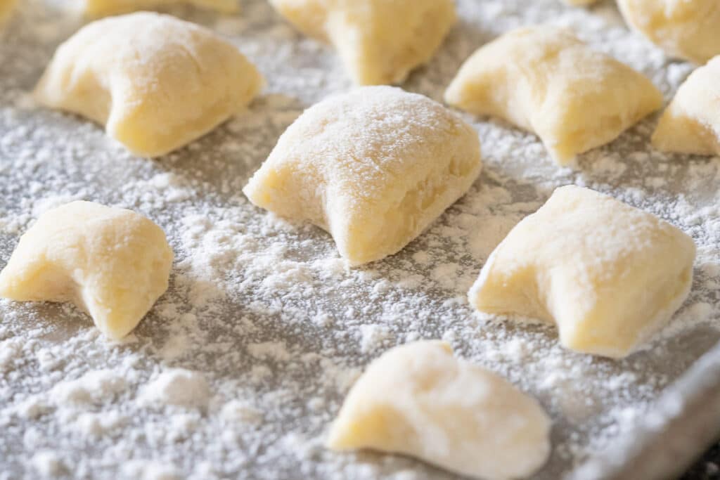 Gnocchi pieces on a well floured baking sheet.