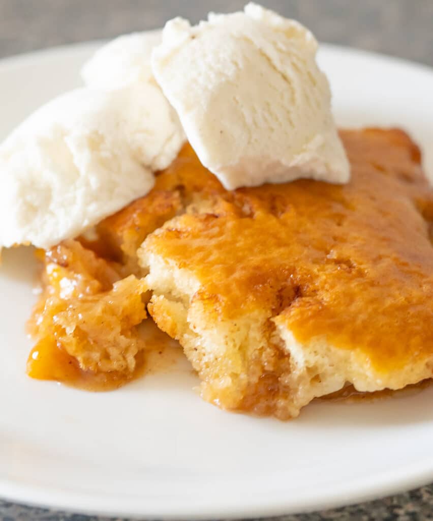 Easy peach cobbler with canned peaches topped with vanilla ice cream.
