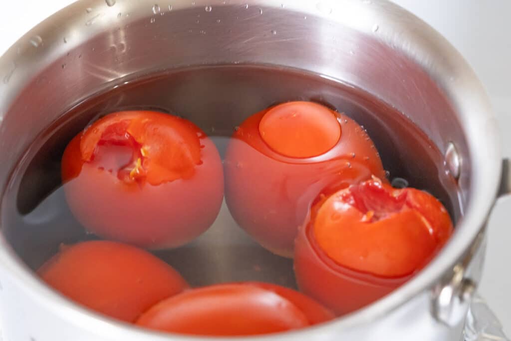 Roma tomatoes in a pot with water.