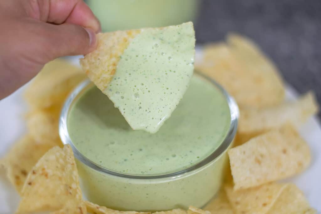 Creamy jalape&ntilde;o dip in a bowl on a plate with chips.