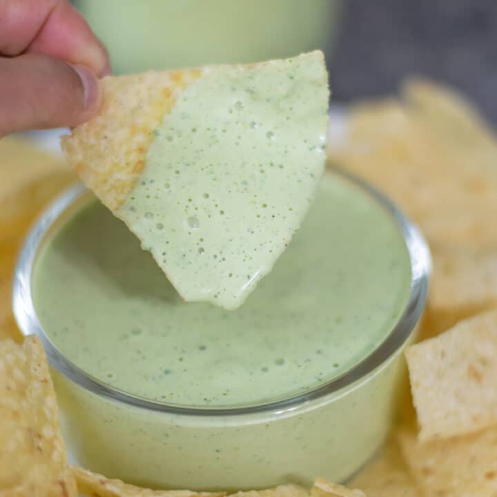 Creamy jalapeño dip in a bowl on a plate with chips.