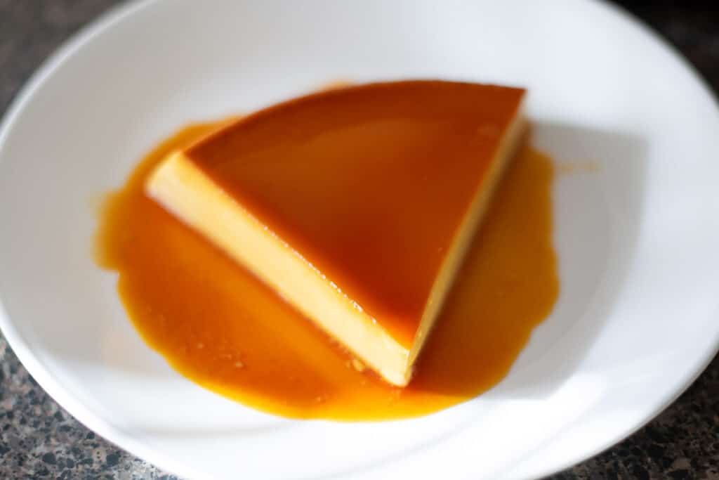 A slice of flan on a white plate.