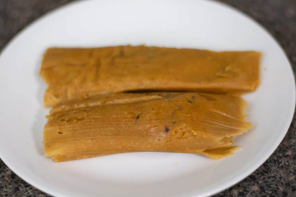 Two beef tamales on a white plate.