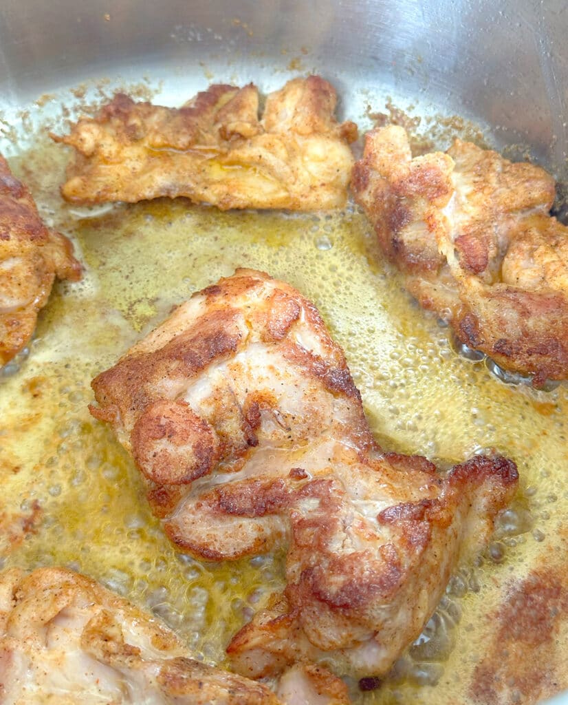 Browning chicken thighs in a pan.